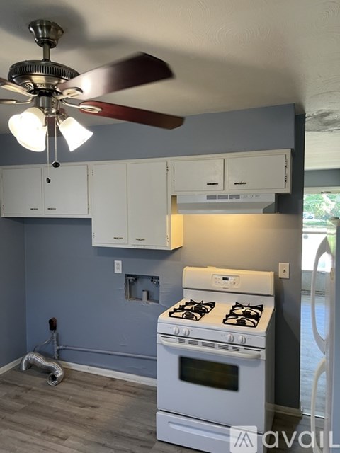 A kitchen with a white stove and a ceiling fan.