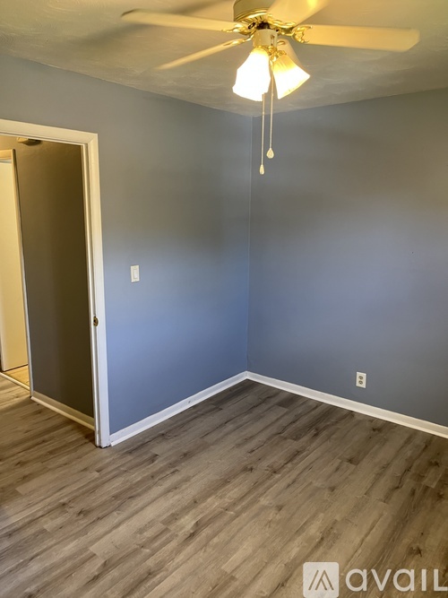 A room with a ceiling fan and wooden flooring.