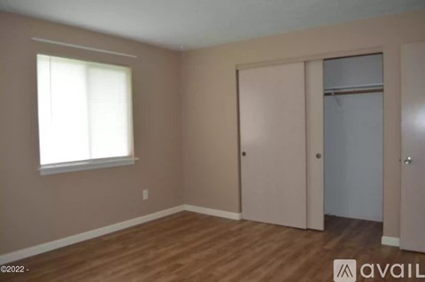 A room with wooden floors and a window with white blinds.