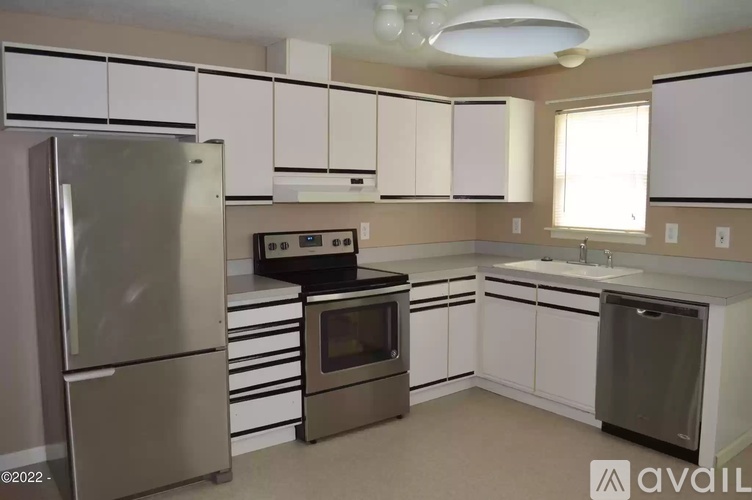 A kitchen with white cabinets and a stainless steel refrigerator.