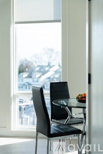 A black chair sits in front of a table with a bowl of fruit on it.