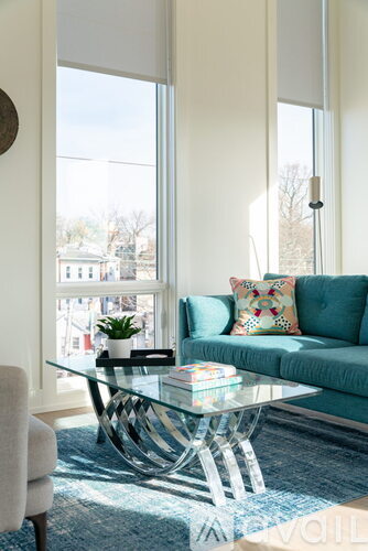 A living room with a blue couch and a glass coffee table.