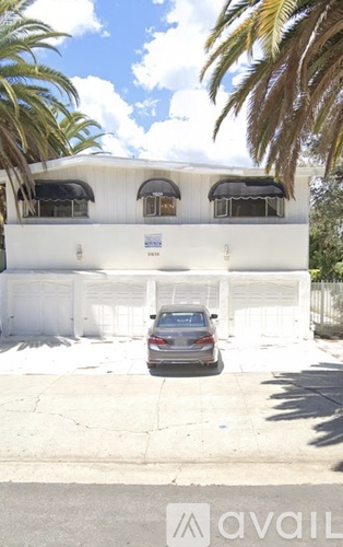 A car is parked in front of a white building with a sign that says "available".
