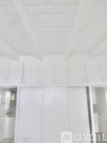 A white kitchen with cabinets and a ceiling with beams.
