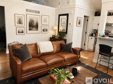 A living room with a brown leather couch and a coffee table with a plant on it.