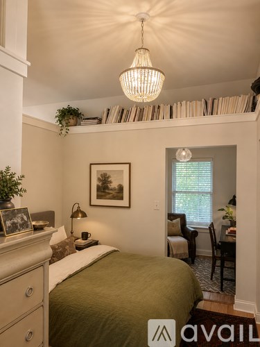 A bedroom with a bed, a dresser, a chair, a lamp, a plant, a picture on the wall, and a window with blinds.