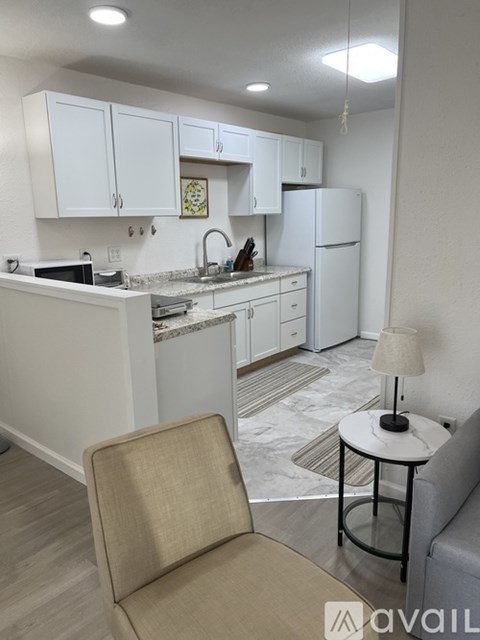 A kitchen with white cabinets and a white refrigerator.