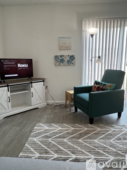 A living room with a green chair and a Roku TV.