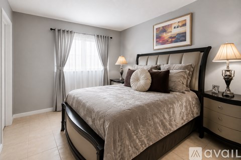 A bedroom with a large bed, a nightstand with a lamp, and a painting on the wall.
