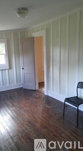 A room with a wooden floor and a black chair.