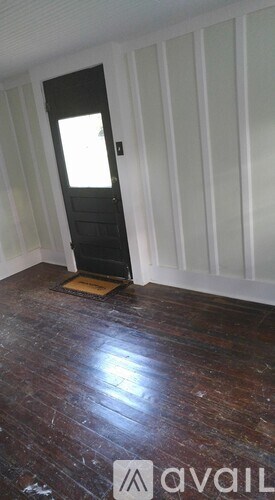 A room with a wooden floor and a black door.