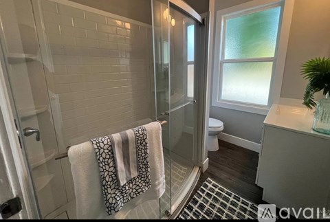 A bathroom with a glass shower door and a towel hanging on the side.