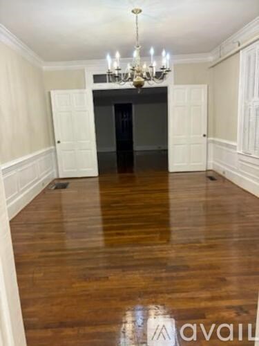 A room with a chandelier and wooden floors.
