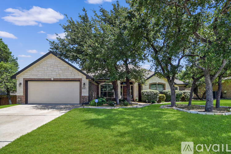 A house with a garage and a tree in front.
