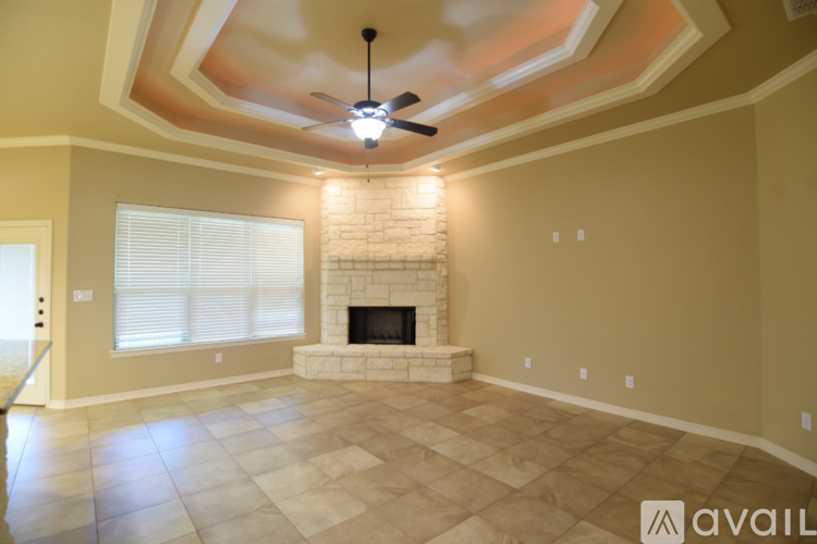 A spacious room with a fireplace and a ceiling fan.