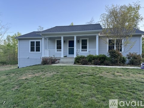 A house with a front porch and a tree in front of it.