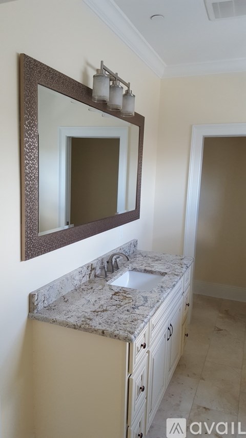 A bathroom with a marble countertop and a large mirror above the sink.