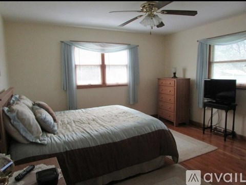 A bedroom with a bed, dresser, and ceiling fan.