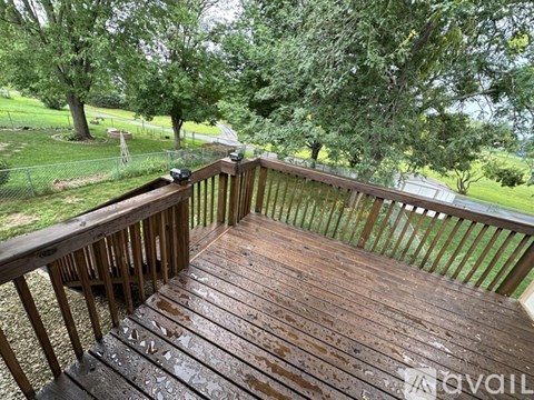 A wooden deck with a railing and trees in the background.