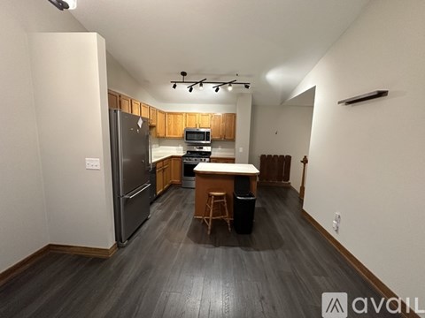 A kitchen with a refrigerator, microwave, and a dining table with chairs.