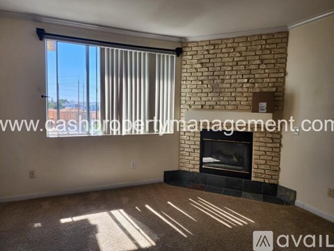 A room with a fireplace and a large window with blinds.