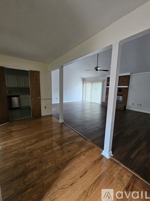 A spacious room with wooden floors and a ceiling fan.
