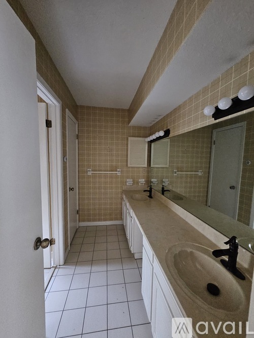 A bathroom with a white door and a brown tiled wall.
