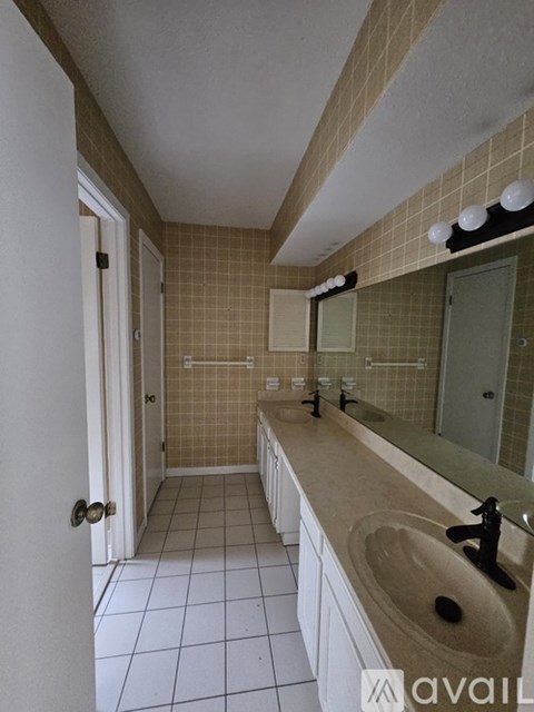 A bathroom with a white door and a brown tiled wall.