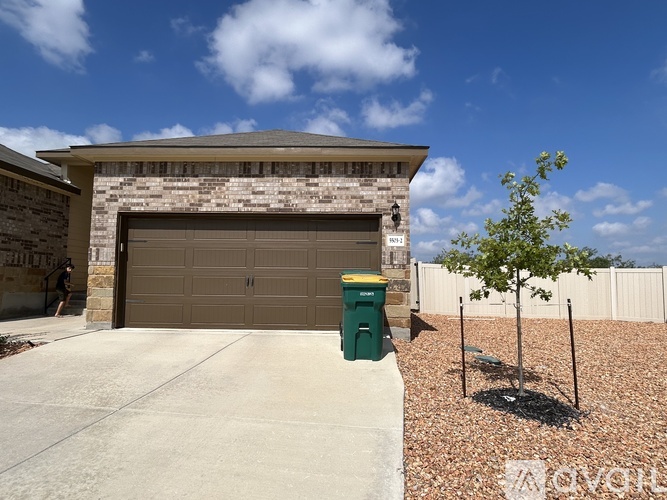 A house with a brown garage door and a green trash can.