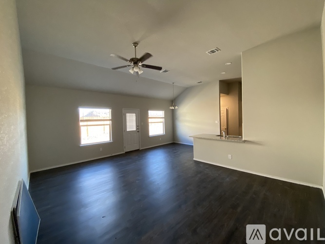 A spacious room with a ceiling fan and wooden flooring.