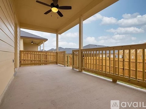 A covered deck with a ceiling fan and a wooden fence.