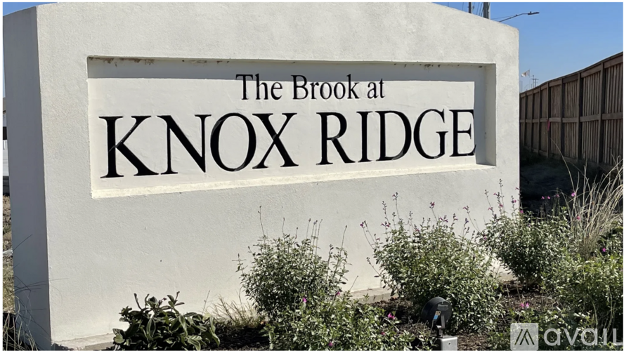 A sign for The Brook at Knox Ridge is displayed in front of some plants.