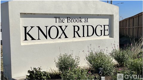 A sign for The Brook at Knox Ridge is displayed in front of some plants.