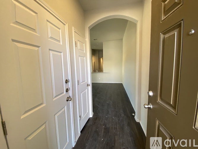 A hallway with white doors and a brown door at the end.