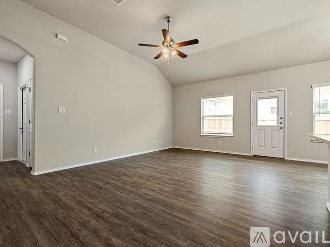 A spacious room with a ceiling fan and hardwood flooring.