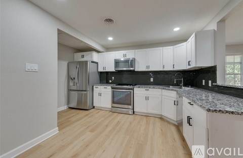 A kitchen with white cabinets and a black countertop.