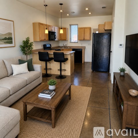 A living room with a couch, a coffee table, and a kitchen area in the background.
