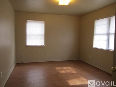 A room with a brown floor and two windows.