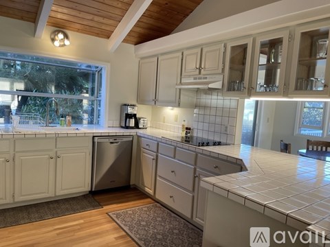 A kitchen with white cabinets and a wooden ceiling.