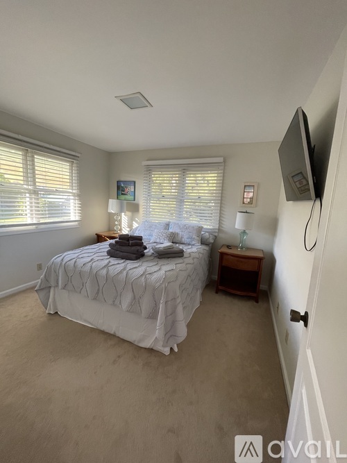 A bedroom with a bed, nightstand, and window with blinds.
