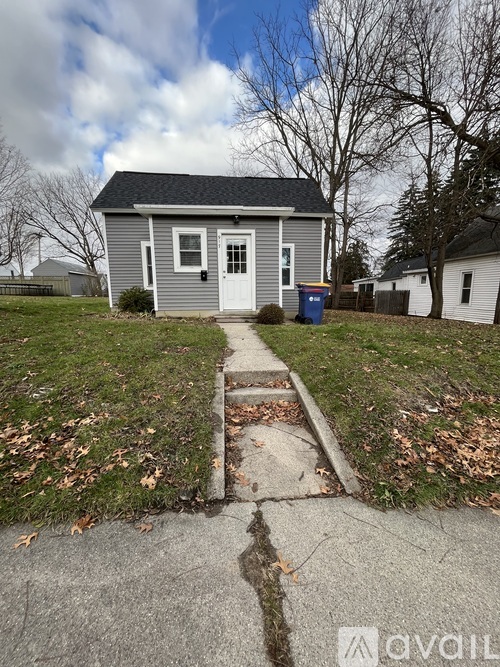 A small grey house with a white door and a small porch.