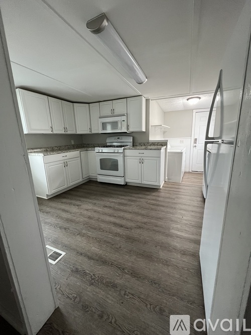 A kitchen with white cabinets and a refrigerator.
