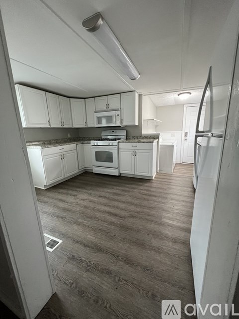 A kitchen with white cabinets and a refrigerator.
