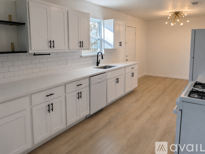 A kitchen with white cabinets and a wooden floor.