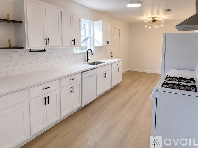 A kitchen with white cabinets and a stove top oven.