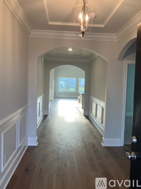 A hallway with a chandelier and a door on the right.