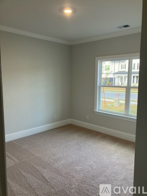 A room with a carpeted floor and a window.