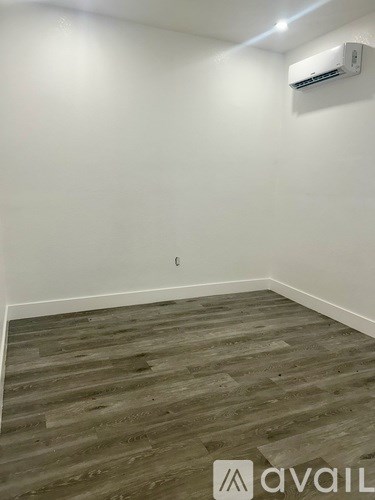 A room with wooden flooring and an air conditioner mounted on the wall.