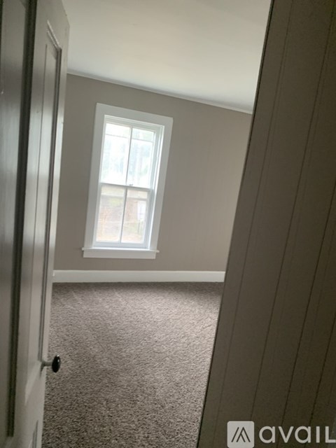 A carpeted room with a window and a closed door.