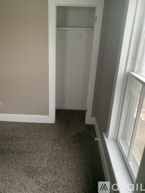 A carpeted room with a white door and a window.